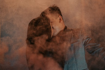 a couple kissing behind red smoke 