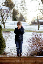 boy praying outdoors in the snow 