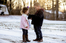 girl and boy child holding a Bible outdoors in snow 