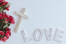 Cross, word love in wood letters and border of red flowers on white