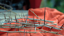 The crown of thorns for the crucifixion of Jesus Christ placed on a red cloth. Focused detail
