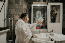 a priest at a baptismal font 