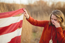 a woman holding a torn American flag and crying 
