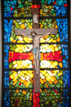 crucifix in front of a stained glass window 