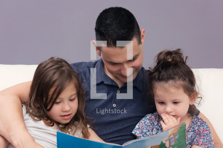Man Reading Holy Bible to his two daughter 