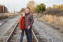 portrait of a couple standing on train tracks 