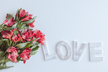 Word love with bouquet of red flowers on a white background with copy space