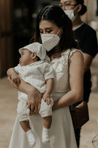 a mother in a face mask at her baby son's christening 