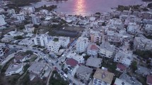 Drone flyover Ksamil downtown revealing Breathtaking sunset over Ionian seascape, Tilt up shot. Albania