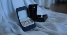 Gold wedding rings of bride and groom, husband and wife together by window light on wedding day.