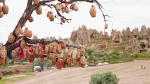 Wish tree with clay jars and jugs in Cappadocia Turkey valley. Famous tradition in touristic place. Old wooden cart with ceramic dish near tree. Sight, landmark in Turkey.
