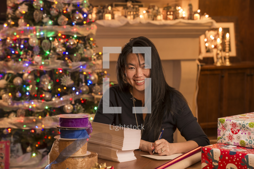 an Asian woman wrapping Christmas gifts 