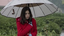 Wet girl standing in the cold rain holding an umbrella
