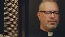 Senior woman confessing her sins through latticed screen of confessional booth, priest giving advice to her during private conversation
