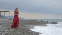 Woman walking along a rocky beach shore. 
