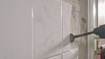 Slow motion of a rotary hammer breaking ceramic tiles off a wall