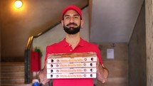 Smiling pizza delivery man giving boxes to customer