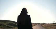 A woman walking toward the sun