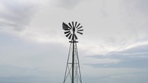 Windmill on a farm in green, summer grass in cinematic slow motion.