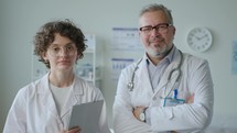 Portrait of Senior Doctor with Young Female Colleague in Clinic
