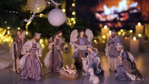 Jesus Christ Nativity scene in atmospheric lights near Christmas tree in front of fireplace. Christmas scene. 