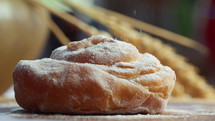 Close up of a wheat bun coated with powdered sugar and sprinkled with caramel crumbs