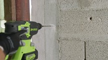 Man drilling hole in concrete wall. Repair works indoors in slow motion