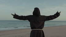 Religious Monk With Prays Towards The Sea With Open Arms