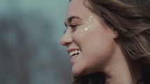 smiling young woman with gold glitter on her face 