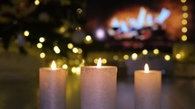 Christmas candles burning in front of the fireplace in atmospheric lights. Christmas atmosphere concept.