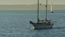 Sailboat passes by with other sailboats in background, slow-motion