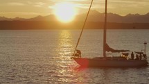Sailboat passes in front of sunset behind Olympic mountain range