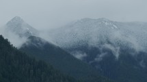 Slow moving clouds pass along snow tipped mountains in Pacific Northwest