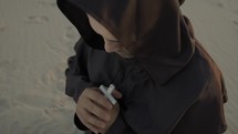 Religious Monk Concentrated In Prayer Kneeling On The Beach Alone