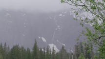 Pan across foggy mountain range with waterfall 