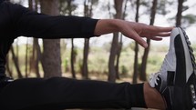 Hand Of A Man Dressed In Black Does Stretching With His Leg On The Tree