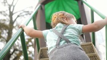 toddler girl climbing up a slide 