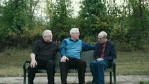 men sitting on a park bench talking 