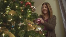 a woman decorating a Christmas tree
