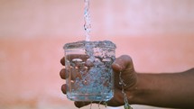 person holding an overflowing cup of water. 