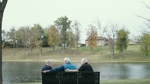 elderly men sitting on a park bench 