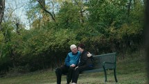 senior couple sitting on a park bench 