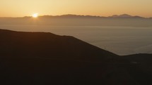 Car drives up road as sun rises in San Francisco Bay