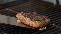 Slow motion of beef hamburger on a grill in close up with flames and smoke.
