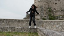 Young Woman Jumps Cheerfully From A Wall