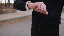 Hand Of A Man Dressed In Black Checks The Smartwatch