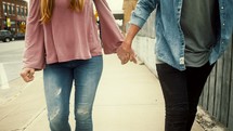 a couple walking down a sidewalk holding hands 