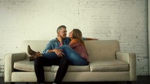a couple talking and kissing on a couch 