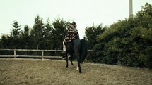 Cowboy riding a black horse on a ranch