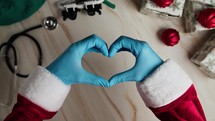 Hand of Santa Claus making heart for sanitary medical christmas background